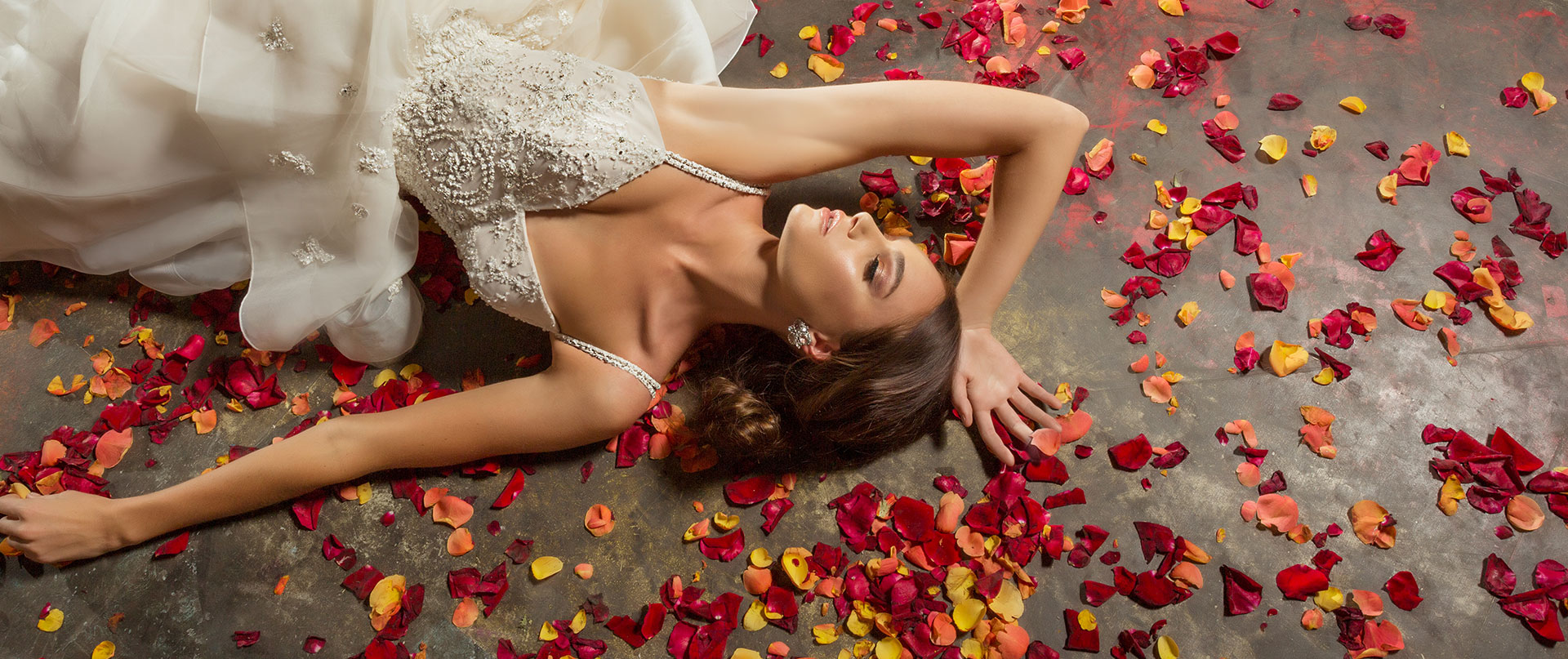 Braut im Hochzeitskleid umgeben von Rosenblättern